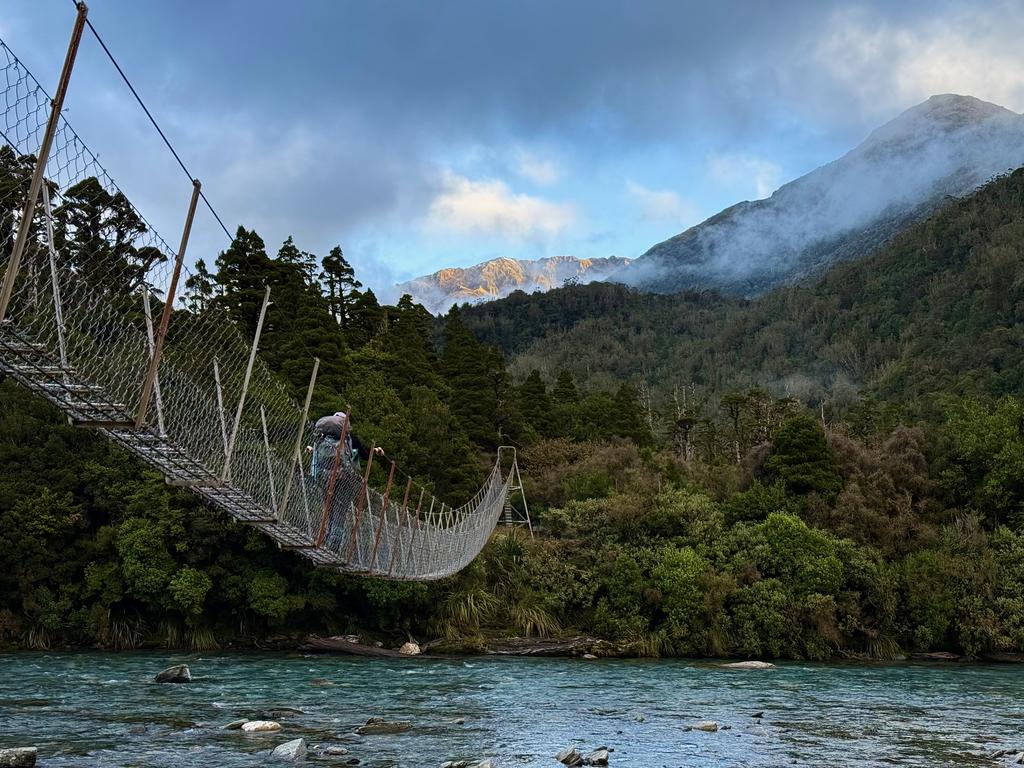 Crossing the Toaroha to the hut with the Southern Alps in the background.